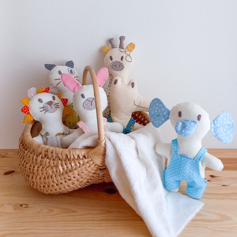 tutti i doudou in un cesto con coperta panna che esce a lato